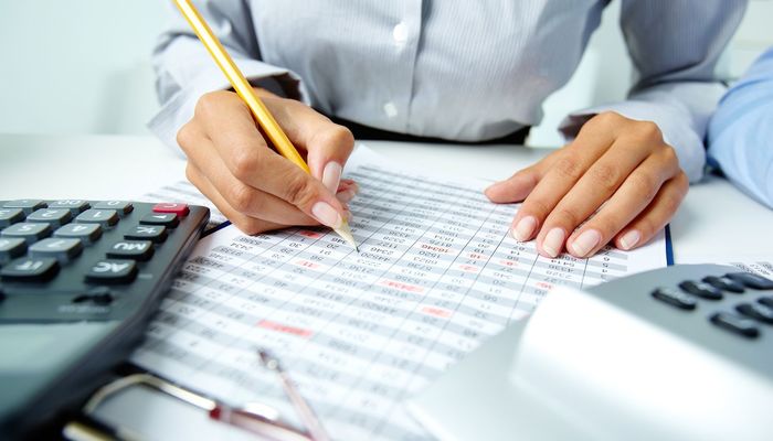 Photo of human hands holding pencil and ticking data in documents