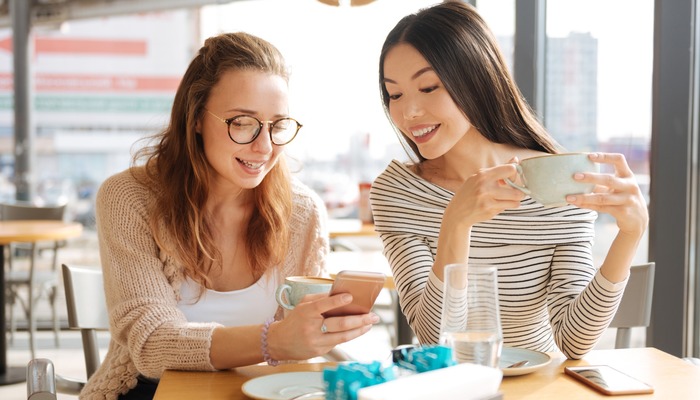 Two girls in a cafe looking at their phones