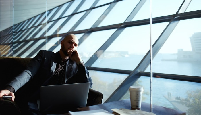 Side shot of handsome successful businessman pensively sitting near the window thinking about the work plan, attractive young business man