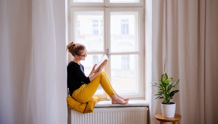 Woman reading a book on her windowsill
